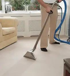 Professional carpet cleaner using a hot-water extraction wand and hose machine in a living room in Pembroke Pines, FL.