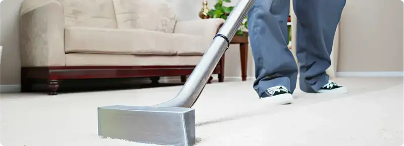 Carpet cleaning technician using a hot-water extraction wand on a light-colored carpet in a living room, Pembroke Pines, FL.