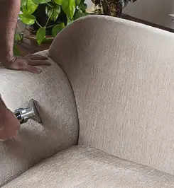 Professional upholstery cleaner deep-cleaning a fabric sofa with a handheld extraction tool and hose Pembroke Pines, FL.