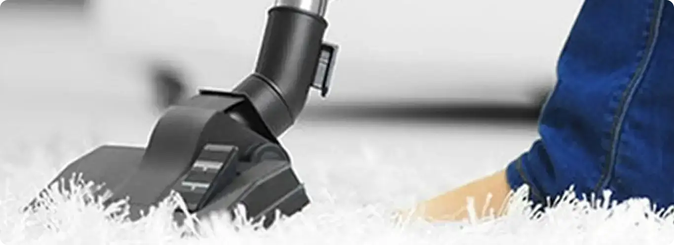 Close-up of a professional vacuuming a white carpet in Hallandale.
