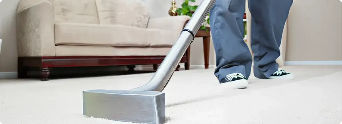 Carpet cleaning technician using a hot-water extraction wand on a light-colored carpet in a living room, Pembroke Pines, FL.